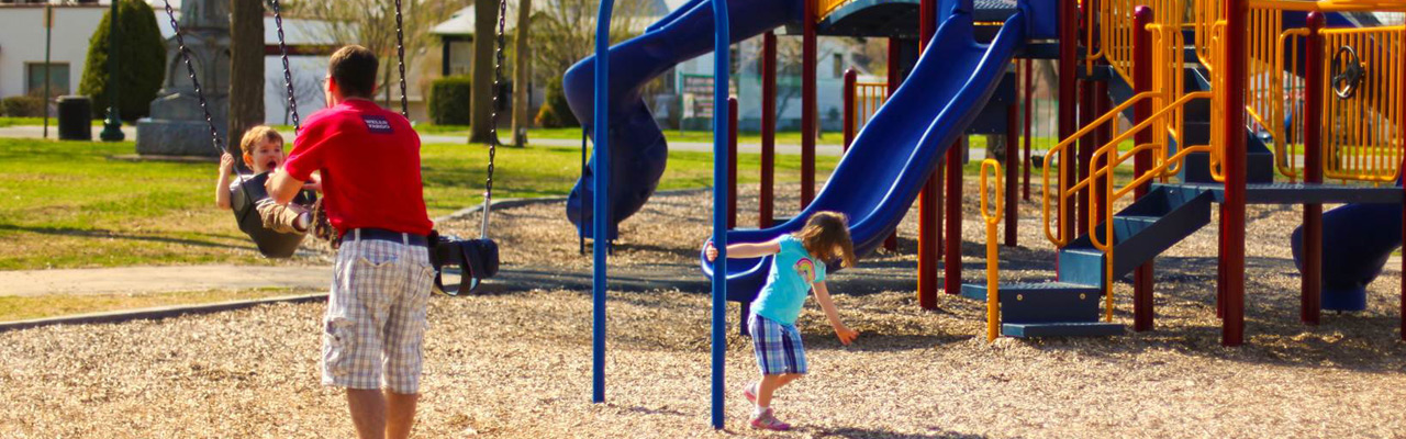 man and kids play at park