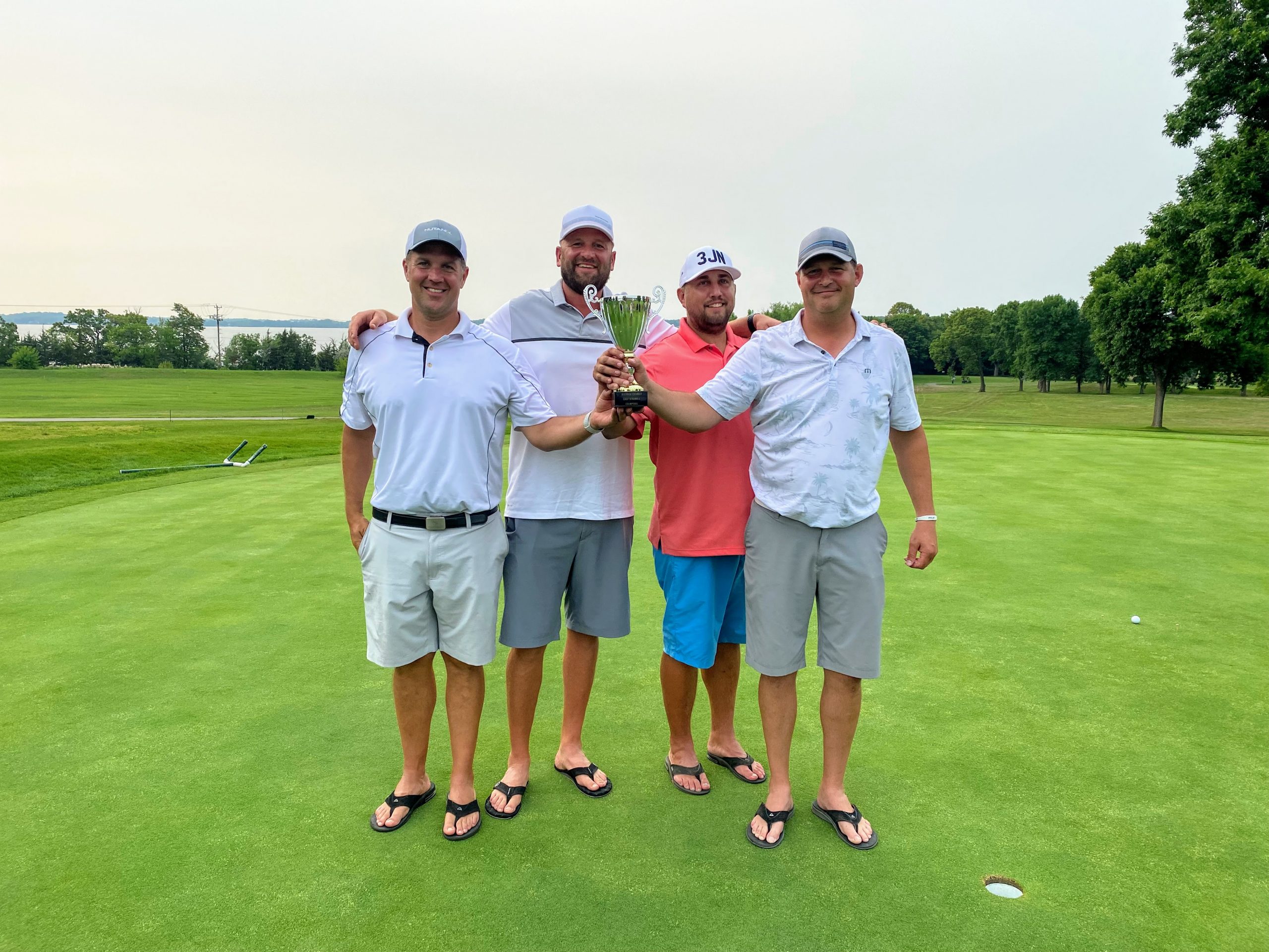 winners of golf tournament hold their trophy