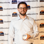 A man named Paul Peterson holding an award shaped like an apple (Golden Apple) on stage.