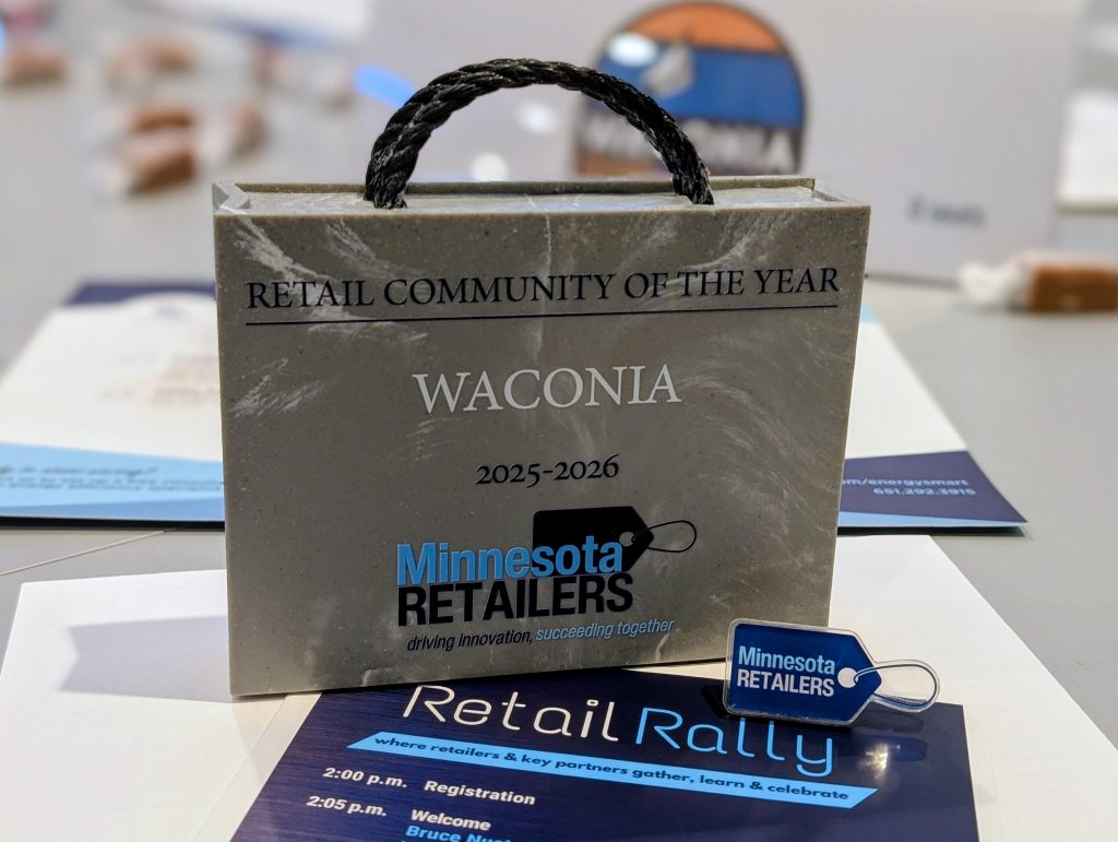 A grey shopping back trophy with Retail Community of the Year Waconia and the MN Retailers Association logo