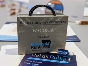 A grey shopping back trophy with Retail Community of the Year Waconia and the MN Retailers Association logo