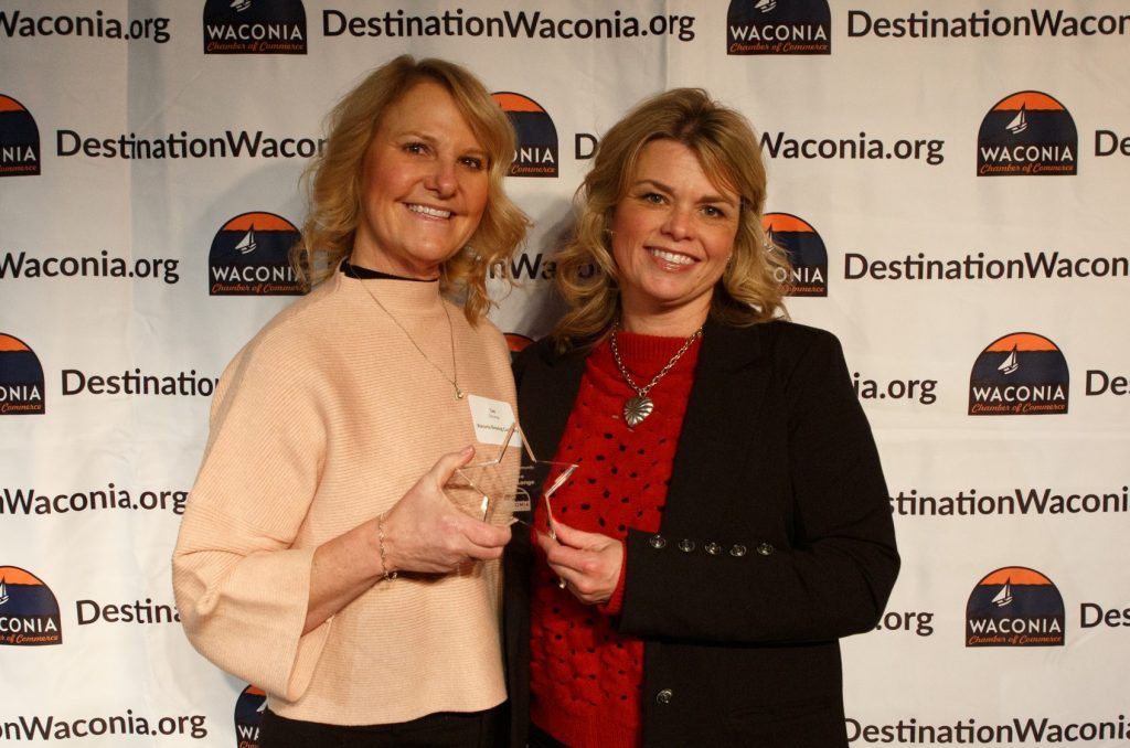 Two women posing with an award trophy