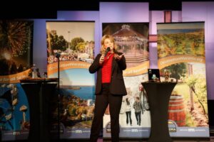 woman on stage speaking into a microphone